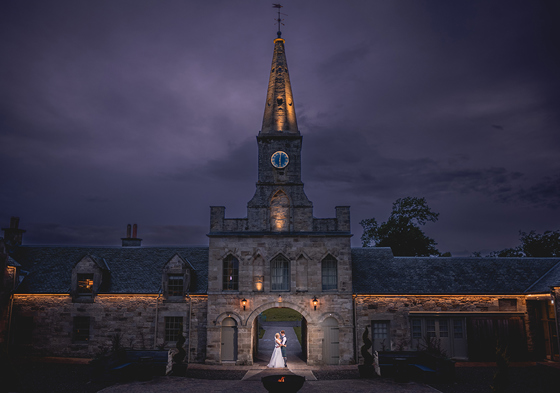 Clock tower with bride and groom embracing in archway